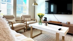 A modern living room with a sofa, two armchairs, a coffee table, a TV, and a vase of flowers. - Your Perfect Getaway – Clean, Modern & Prime Location (Greer)