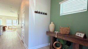 A hallway with a wooden floor, a coat rack, a shelf with decorative items, and a calendar. - Your Perfect Getaway – Clean, Modern & Prime Location (Greer)