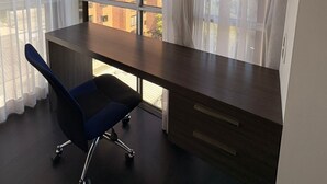 A modern office space with a desk, chair, and large window with curtains.