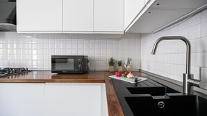 Une cuisine moderne avec des armoires blanches, un évier en acier inoxydable et un four à micro-ondes.