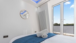 A hotel room with a bed, a round mirror, a radiator, and a sliding glass door to an outdoor area. - Elegant 2BR flat near Waterloo Station| Big Ben | London Eye (London)
