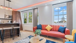 A modern living room with a sofa, coffee table, and bar area with stools. - Elegant 2BR flat near Waterloo Station| Big Ben | London Eye (London)