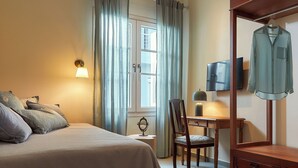 Een hotelkamer met een bed, een bureau, een stoel, een televisie en een kledingrek.