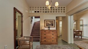 Een hal met een houten dressoir, een spiegel, een trap en een eethoek.