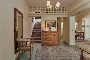 A hallway with a wooden dresser, a mirror, a staircase, and a dining area.