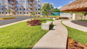 A residential building with multiple balconies, a parking area, and a well-maintained lawn. - Cancun apartment with pool, AC and Pet Friendly (Cancún)