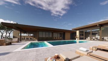 A modern outdoor pool area with lounge seating and a stone facade building.