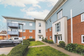 A multi-story residential building with a flat roof, a visible front door, and a small front yard with a pathway. - Spacious 2BDR 2Bath Apt with Parking Near Heathrow (Greater London)