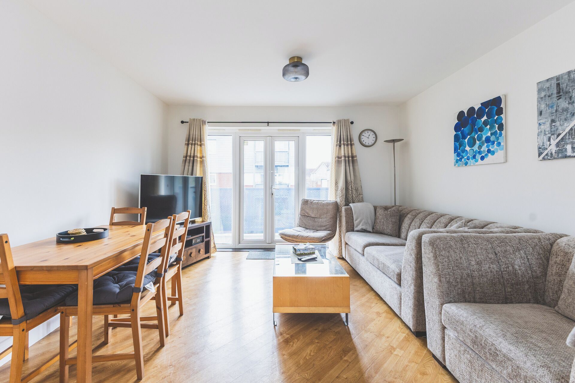 A living room with a sofa, a coffee table, a TV, and a dining area with chairs and a table.