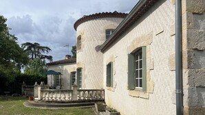 Ein Steinhaus mit einem runden Turm, einem Balkon mit Geländer und einem kleinen Garten mit Pflanzkästen.