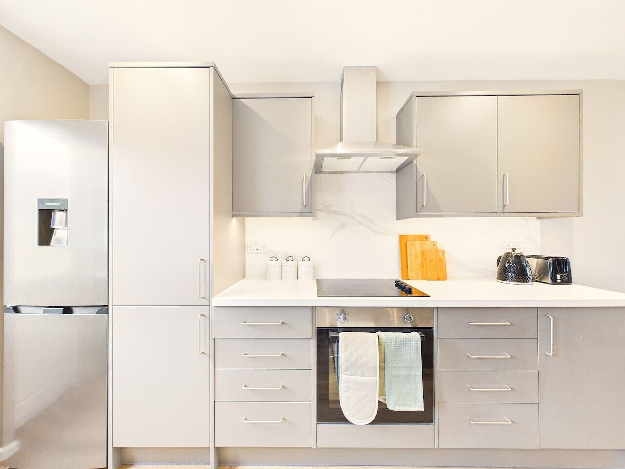 A modern kitchen with stainless steel appliances, a built-in oven, and a countertop with a toaster and a kettle.