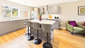 Una cocina moderna con una isla central, taburetes de bar y una zona de comedor.