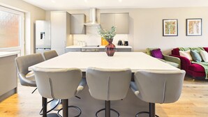Una cocina moderna con una isla central, una zona de comedor con sillas y un sofá rojo en la sala de estar.