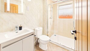 Un baño con ducha, inodoro, lavabo y espejo.