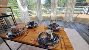 A dining table set with plates, cups, and cutlery, with a view of a wooden deck and greenery through large windows. - Hain Glamp Karkonosze – glamping tent with jacuzzi & sauna (Przesieka)