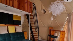 A cozy living area with a sofa, a wooden coffee table, a ladder, and a desk. - Hain Glamp Karkonosze – glamping tent with jacuzzi & sauna (Przesieka)