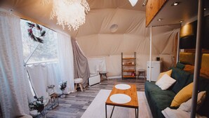 A tented accommodation with a wooden table, green sofa, and a small kitchenette. - Hain Glamp Karkonosze – glamping tent with jacuzzi & sauna (Przesieka)