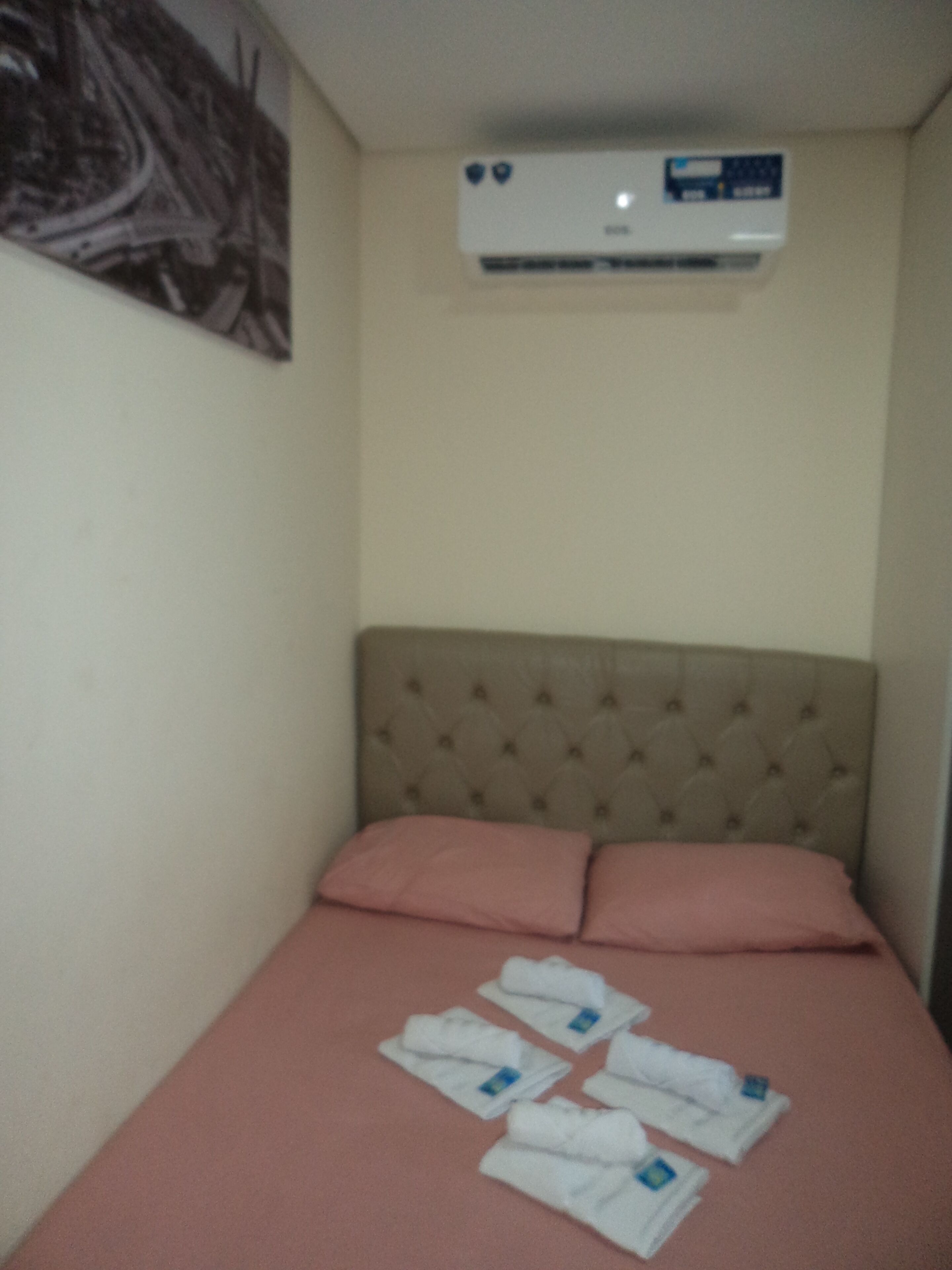 A bedroom with a bed, pillows, and a wall-mounted air conditioner.