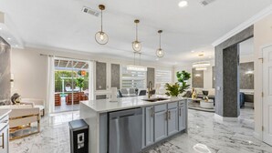 A modern kitchen with a marble countertop, grey cabinets, and pendant lighting. - 355 Luxury House | Patio | GameRoom | Pool | Grill (Davenport)