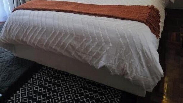Ein modernes Hotelzimmer mit einem großen Bett, einer Couch und einer Wandleuchte.