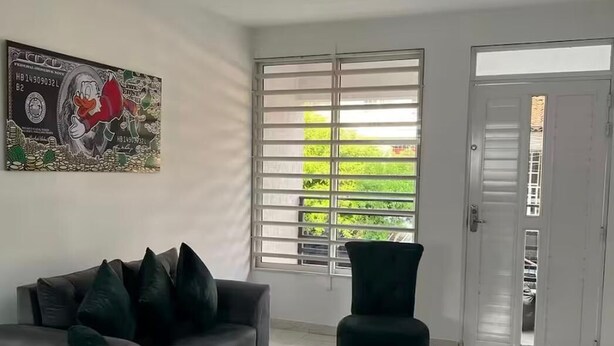 A living room with a sofa, two chairs, a large window with blinds, and a door leading to another room. - Family Apt in the South of Cali (Cali)