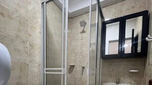 A bathroom with a glass-enclosed shower, a toilet, a sink, and a mirror. - Family Apt in the South of Cali (Cali)