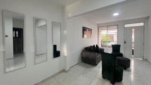 A spacious room with a large mirror, a sofa, and a window with blinds. - Family Apt in the South of Cali (Cali)