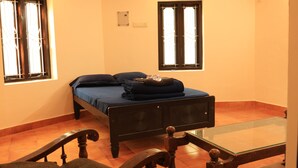 Una stanza con un letto, un tavolino in vetro e due finestre con tende.