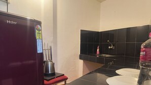 Una cucina compatta con un frigorifero Haier, una moka, un lavandino e una bottiglia d'acqua.