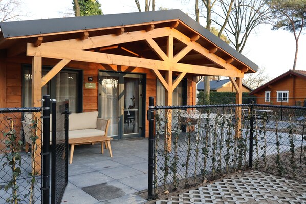 Une cabane en bois avec une véranda couverte, un banc et une porte.
