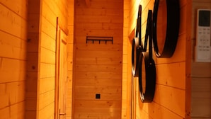 A wooden hallway with a ceiling light, wooden walls, and a door at the end. - Luxury Wooden Wellness Forest House with Sauna -Amora 174 (Eindhoven)