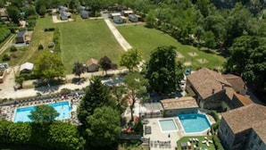 An aerial view of a residential area with a swimming pool, multiple houses, and a large lawn. - COTTAGE PARKS MEDROSE Ecolodge tent with sanitary facilities (Saint-Thomé)