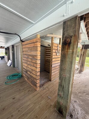 A wooden structure under a building, possibly a sauna or hot tub area, with a wooden floor and a green hose on the ground. -  Vitamin Sea is your Exclusive Waterfront Escape, Private Beach & Dock (Captiva)