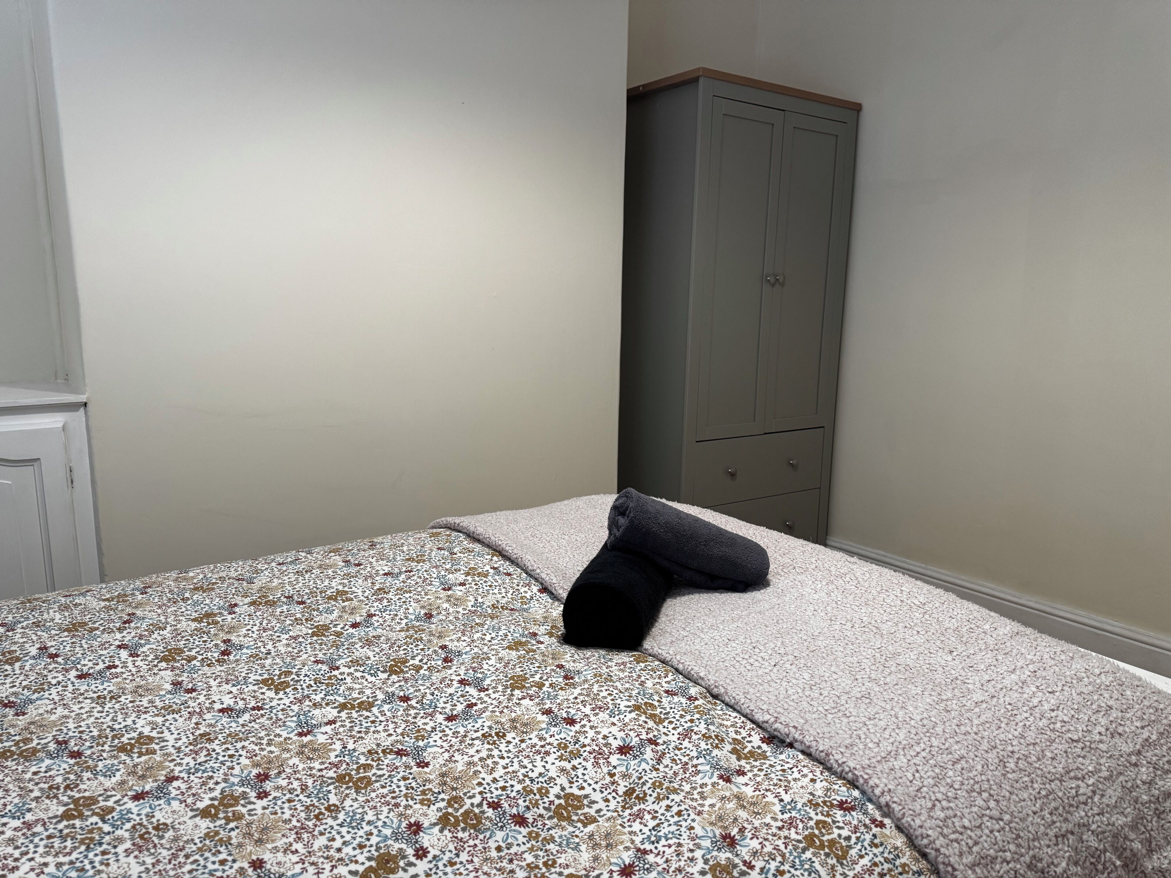 A bedroom with a bed, a grey wardrobe, and a white door.