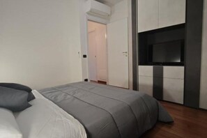 Un dormitorio con cama, televisor y armario.