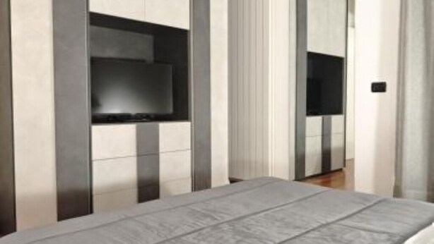 Ett modernt hotellrum med en stor säng, en inbyggd TV och en minimalistisk design.