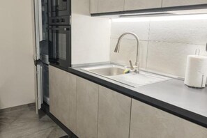 Una cocina moderna con un lavamanos de acero inoxidable, horno empotrado y encimera negra.