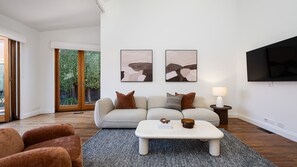A modern living room with a sofa, coffee table, and artwork on the wall.