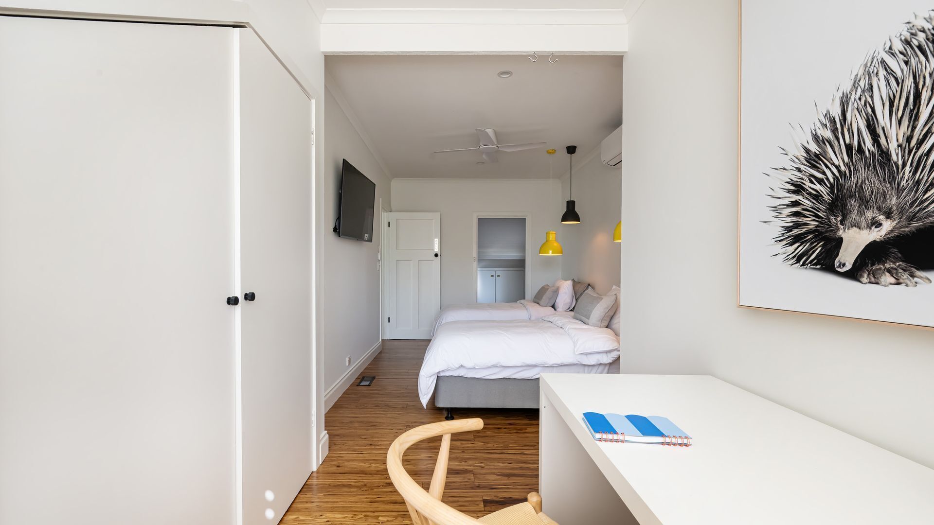 A bedroom with a bed, bedside table, chair, and a desk with a notebook.