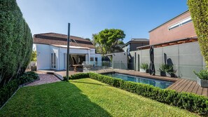 A residential backyard with a swimming pool, a patio, and a fenced area.
