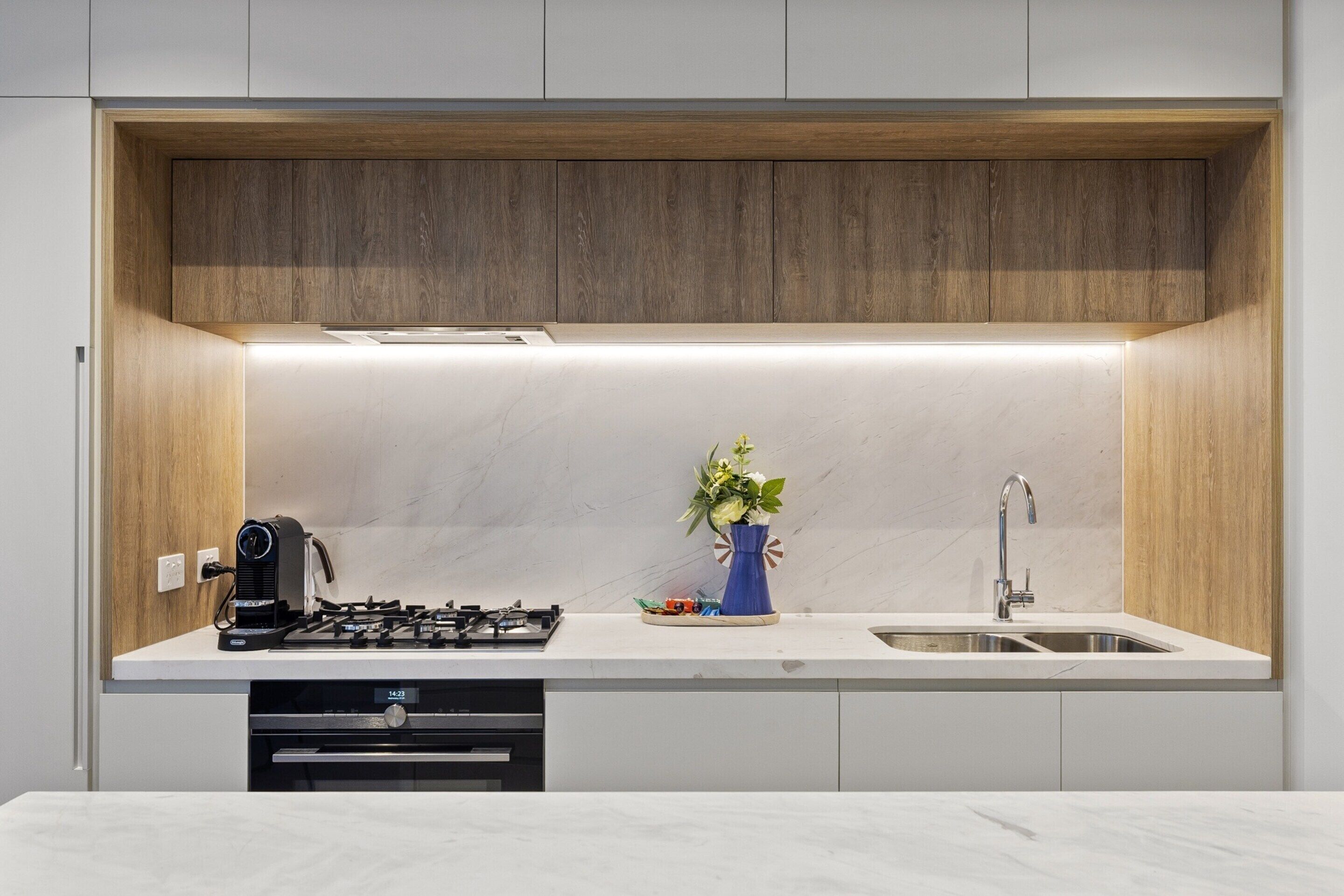 Una cocina moderna con estufa integrada, un lavamanos y un armario superior de madera.