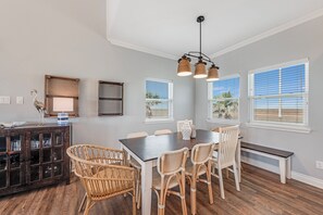 A dining area with a dark wooden table, wicker chairs, and a ceiling light fixture. - This fabulous pet friendly home with downstairs game room/apartment and just a s (Port Aransas)