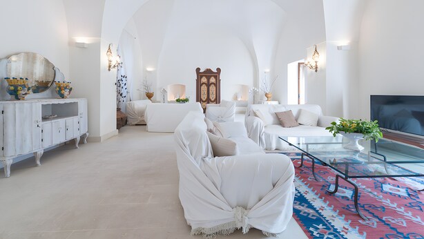 Un salón espacioso con un techo alto en arco, muebles blancos y un espejo grande.