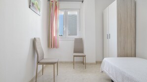 A bedroom with a bed, two chairs, a window with curtains, and a wardrobe. - Casa Andrés – Families Only, with Balcony, Wi-Fi, and Air Conditioning (Conil de la Frontera)