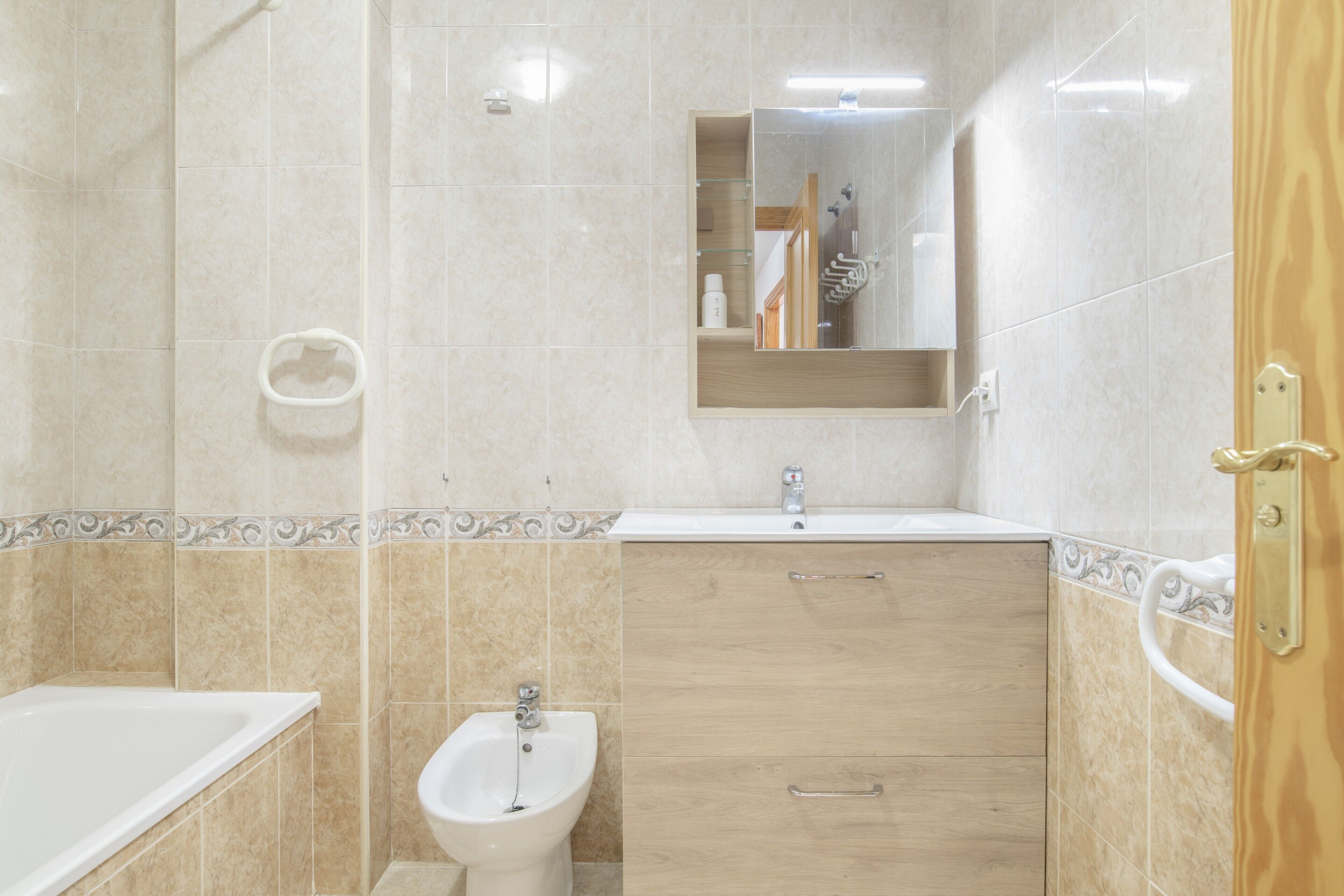 Ein Badezimmer mit Badewanne, Bidet, Spiegel und einem hölzernen Waschtisch.