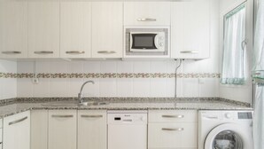 A kitchen with white cabinets, a microwave, a dishwasher, and a washing machine. - Casa Andrés – Families Only, with Balcony, Wi-Fi, and Air Conditioning (Conil de la Frontera)