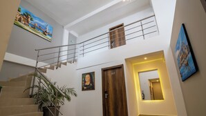 Un interior de varios niveles con una escalera, puertas de madera y obras de arte en las paredes.