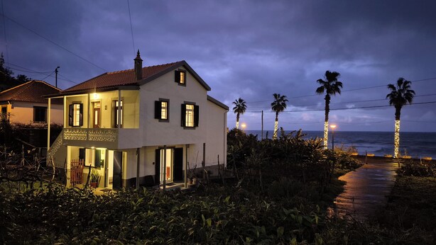Une maison à deux étages avec un balcon, un escalier et une vue sur l’océan.