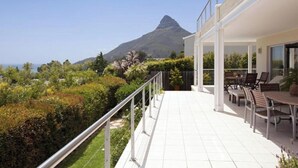 Ein modernes Haus mit Balkon und Blick auf einen Garten sowie einen Berg.