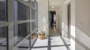 A hallway with glass doors, a tiled floor, and wicker baskets with flowers. - BES 6 - Minimal Studio by GHH (Kesariani)